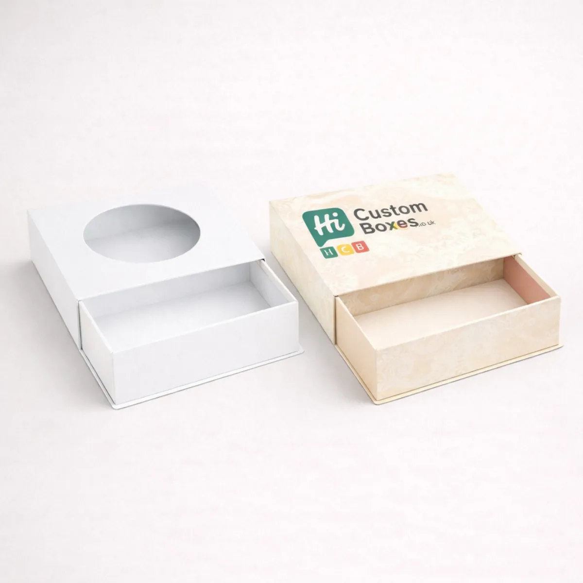 Two drawer-style boxes with circular windows- one plain white and one with a cream damask pattern- class=